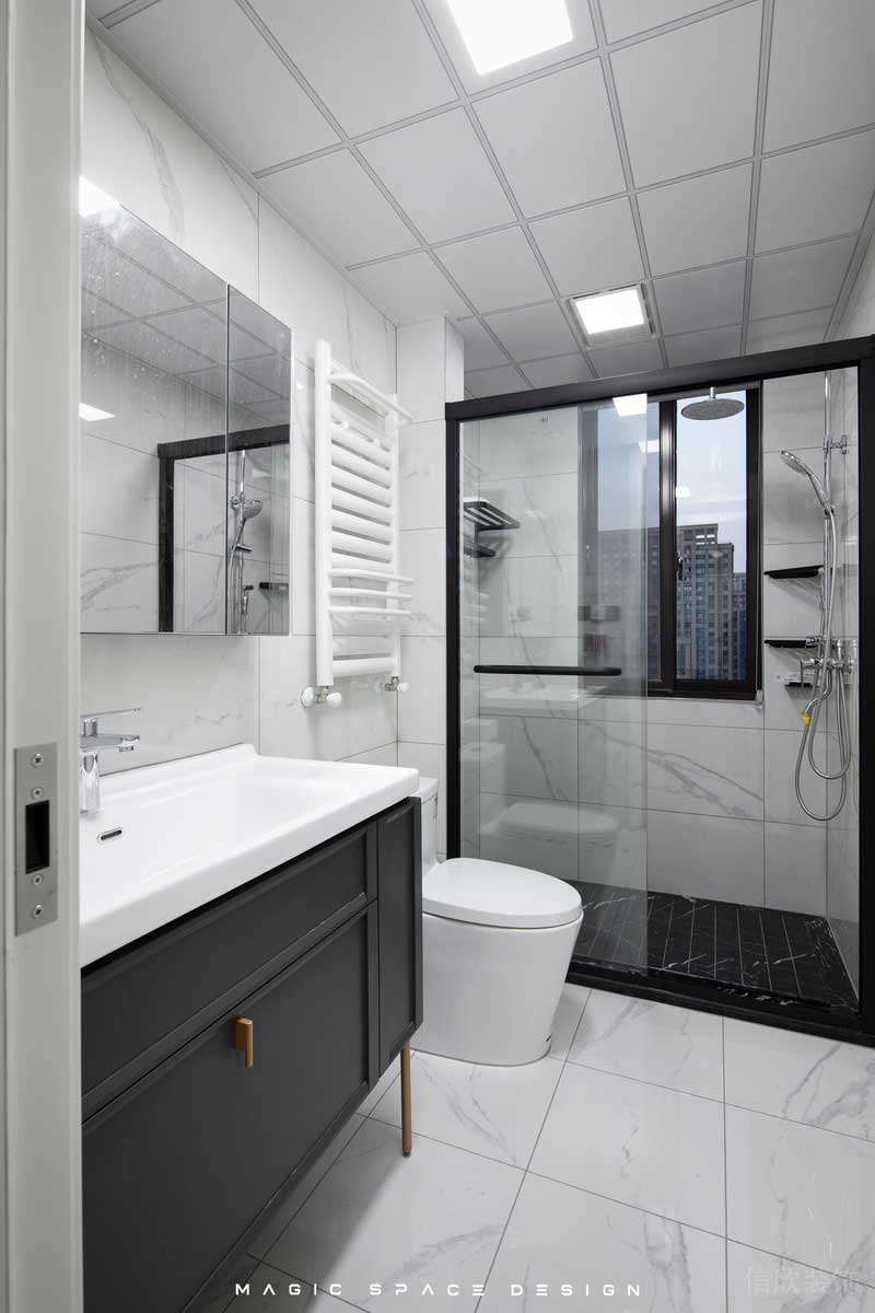 白色的大理石磚面主衛(wèi)空間黑色邊框的淋浴拉門，搭配上深黑的防滑地磚。